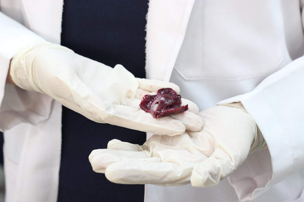 a person wearing white gloves holding a piece of fruit