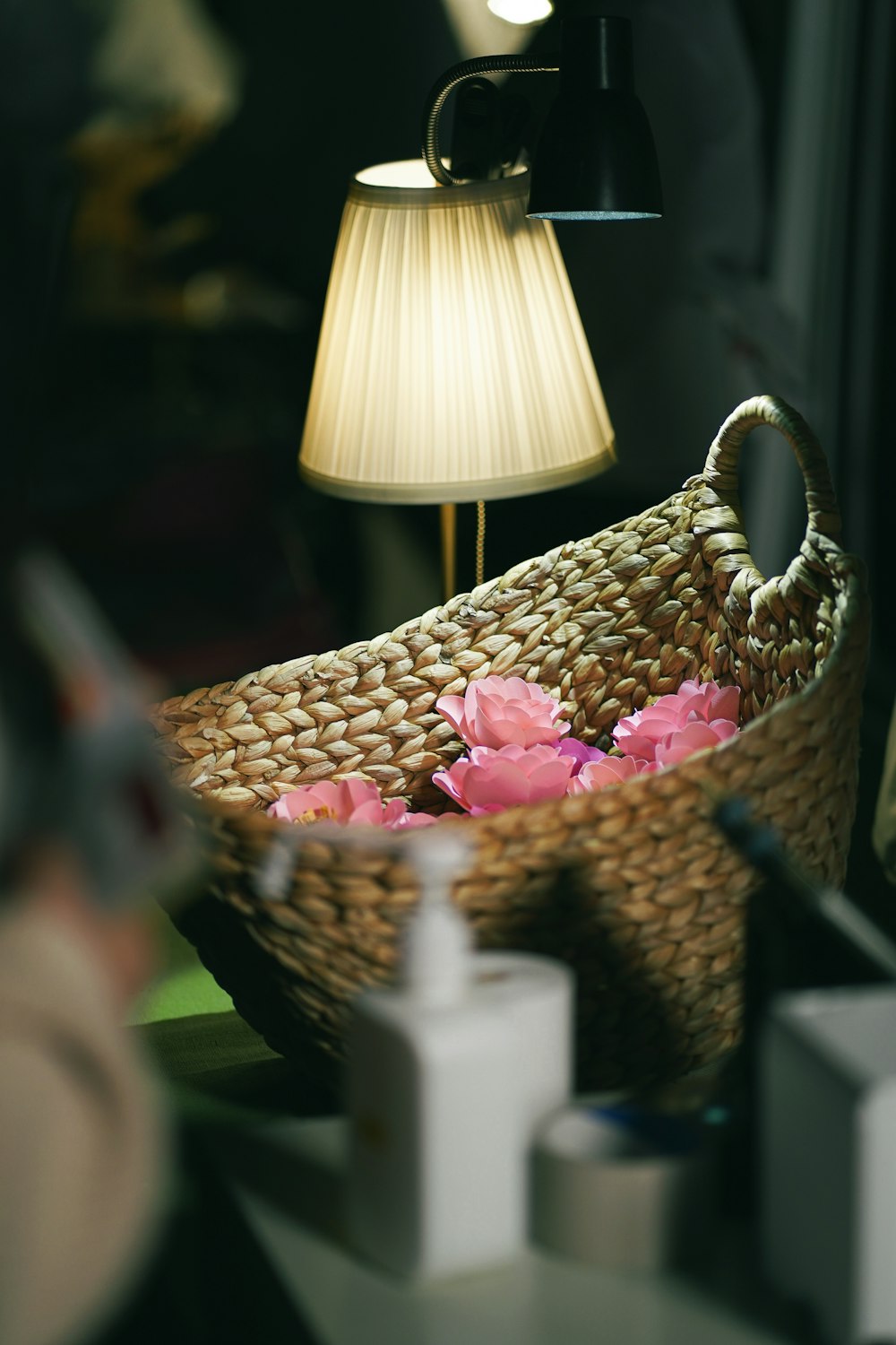 a basket with flowers in it sitting next to a lamp