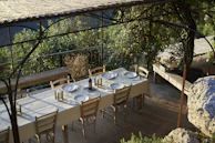 A table set outdoors under a pergola, ready for a family meal.