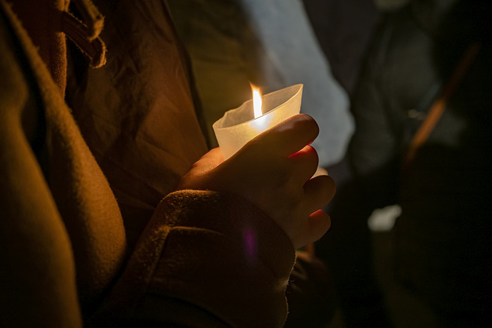 a person holding a lit candle in their hand