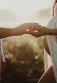 Tender moment of couple holding hands bathed in soft golden light.