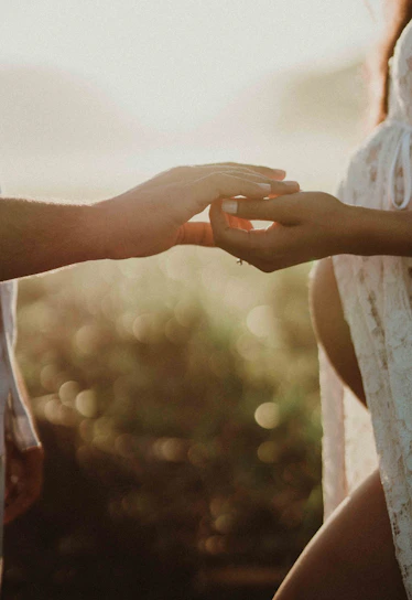 A warm, candid moment of a married couple holding hands and smiling gently in soft natural light.