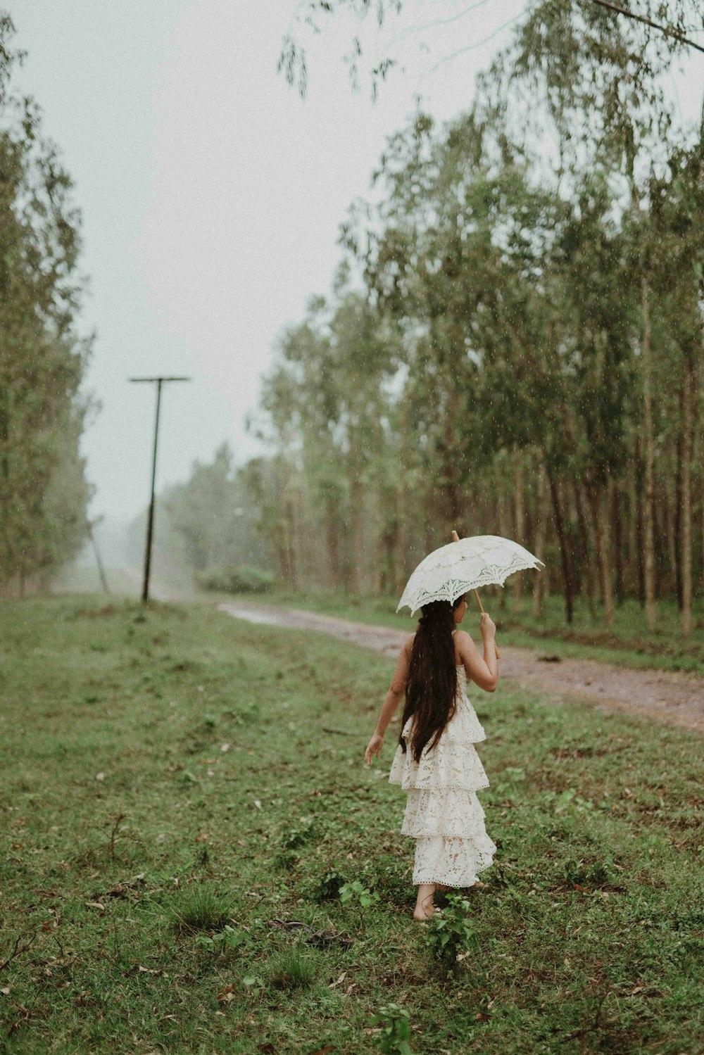 a girl in a white dress holding an umbrella