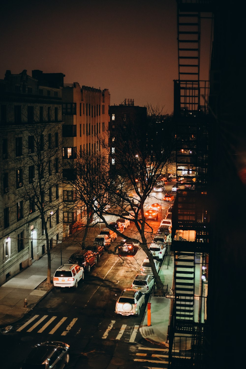 Una calle de la ciudad por la noche con coches aparcados al costado de la carretera