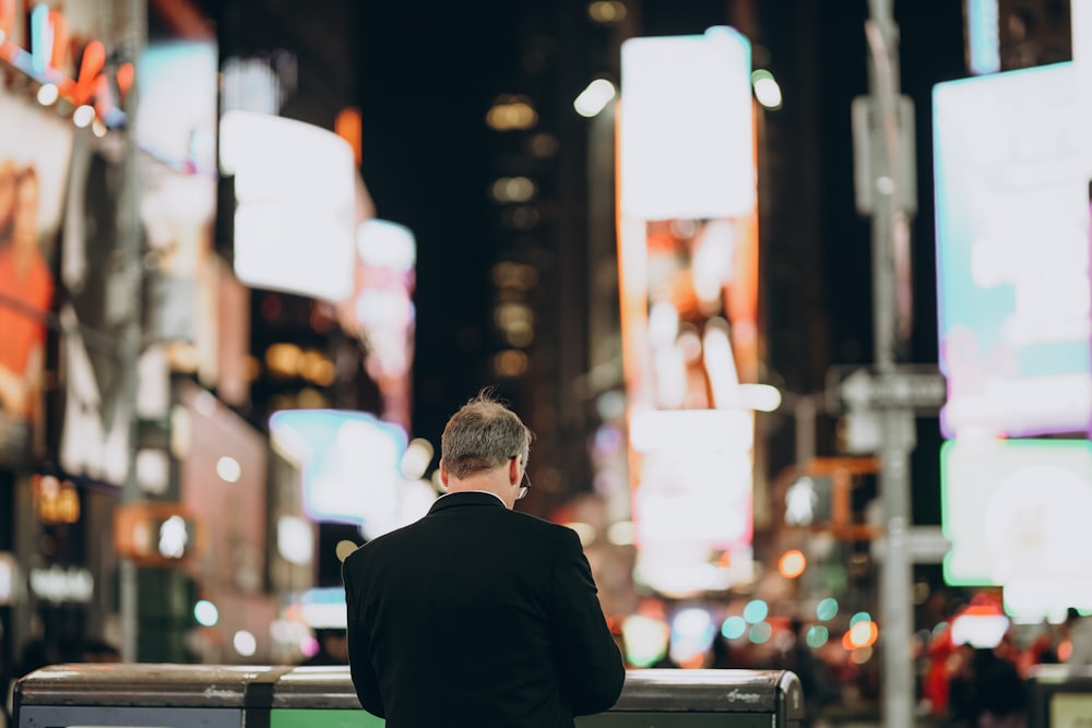 a man sitting on a bench in a city at night
