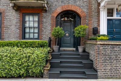 Elegant townhouse with red door and green shrubs.