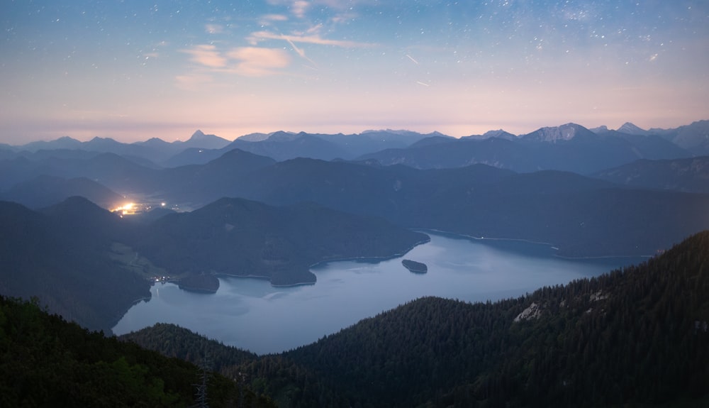 a view of a lake surrounded by mountains at night