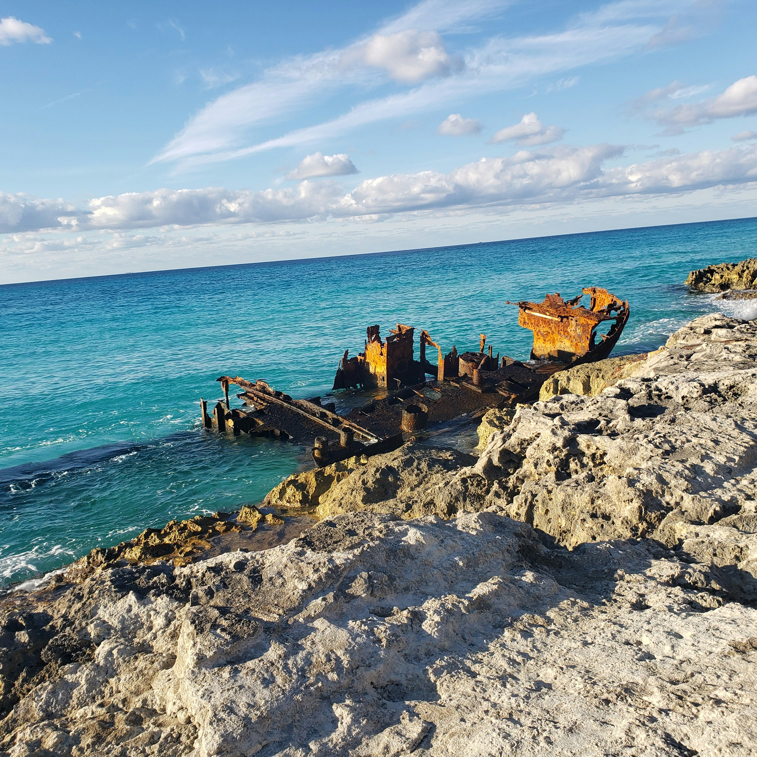 A rusty boat sitting on top of a rocky beach photo – Free Shipwreck ...