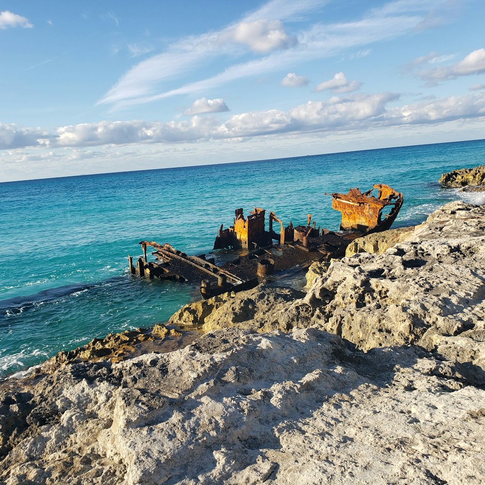 Un bateau rouillé assis au sommet d’une plage rocheuse