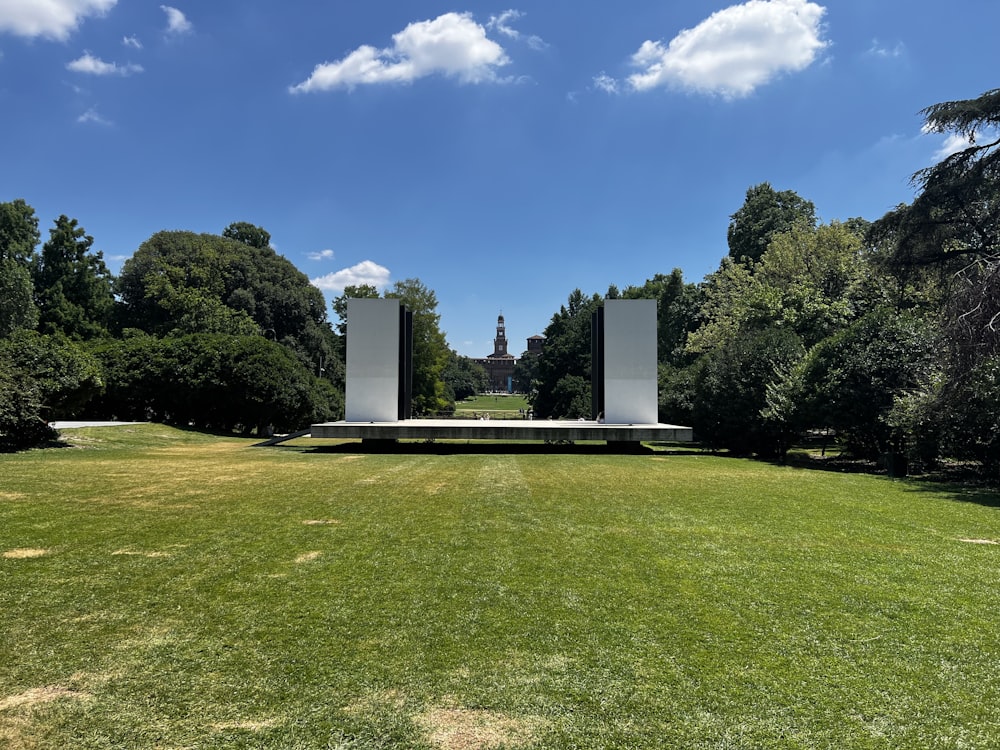 a grassy field with two white pillars in the middle of it