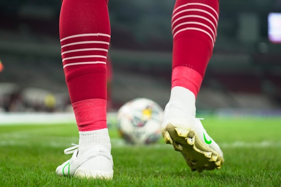 a close up of a soccer player's feet with a ball in the background