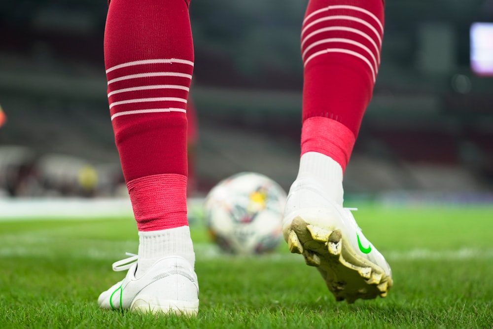 a close up of a soccer player's feet with a ball in the background