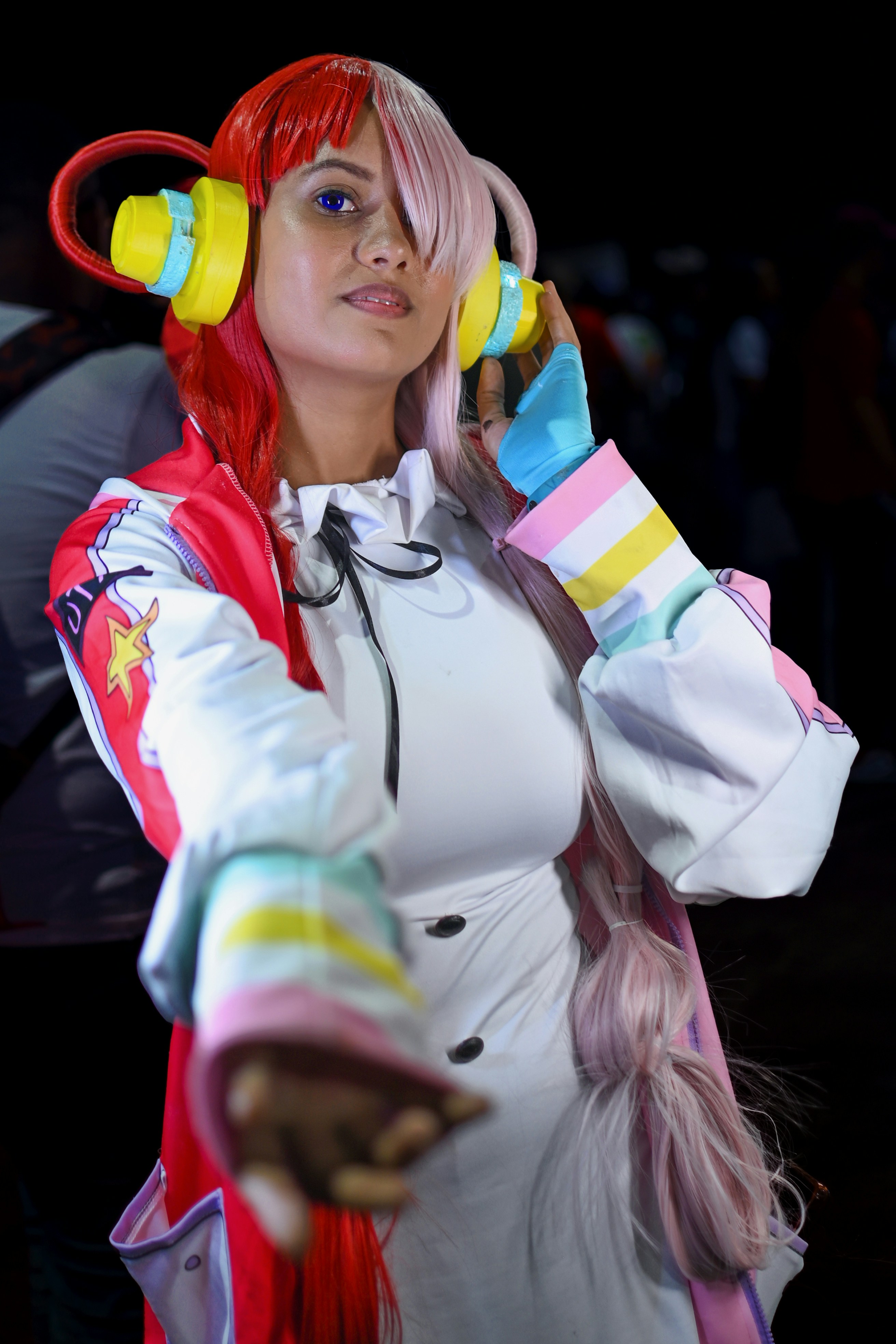 Seorang wanita dengan rambut merah muda mengenakan headphone