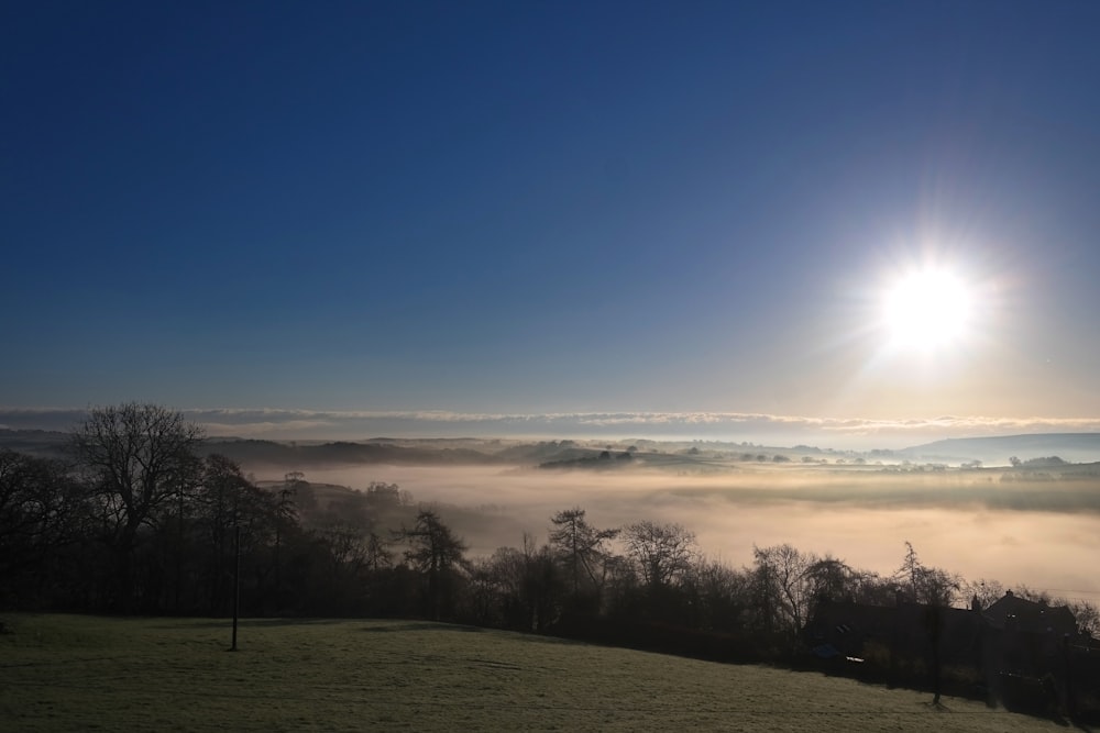 the sun is shining over a foggy valley