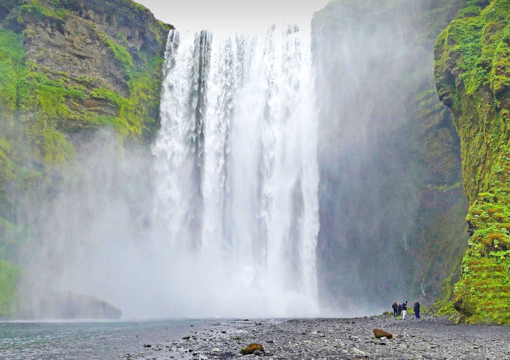 a group of people standing in front of a waterfall