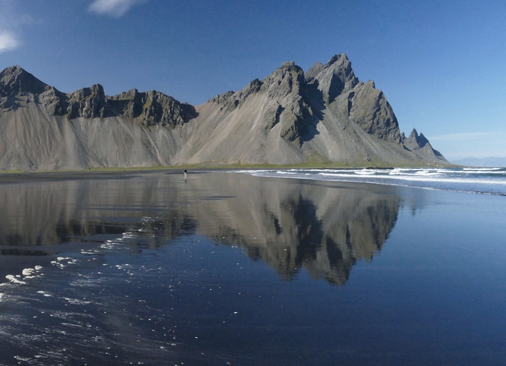 a person walking on a beach with mountains in the background