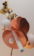 A surreal composition featuring a combination of natural and abstract elements. There are curved, fan-like structures in shades of orange, alongside spherical and tubular shapes with a textured appearance. Yellow, brown-hued flowers with subtle details intertwine with these elements, creating a harmonious balance of organic and geometric forms.