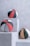 Three basketballs with modern designs are placed on white, textured stone pedestals against a cracked, light gray wall. The balls feature patterns in black, red, white, and orange, including stripes and solid panels.