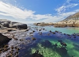 a body of water surrounded by rocks under a blue sky