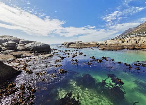 a body of water surrounded by rocks under a blue sky