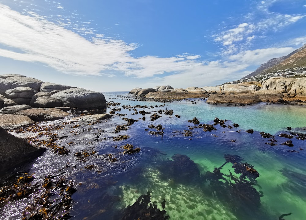 a body of water surrounded by rocks under a blue sky