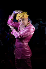 Billy Francesca striking a dynamic pose in a dazzling hot pink and teal outfit under bright stage lights.