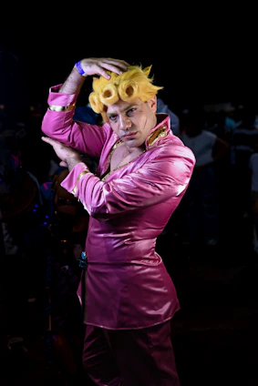 Billy Francesca striking a dynamic pose in a dazzling hot pink and teal outfit under bright stage lights.