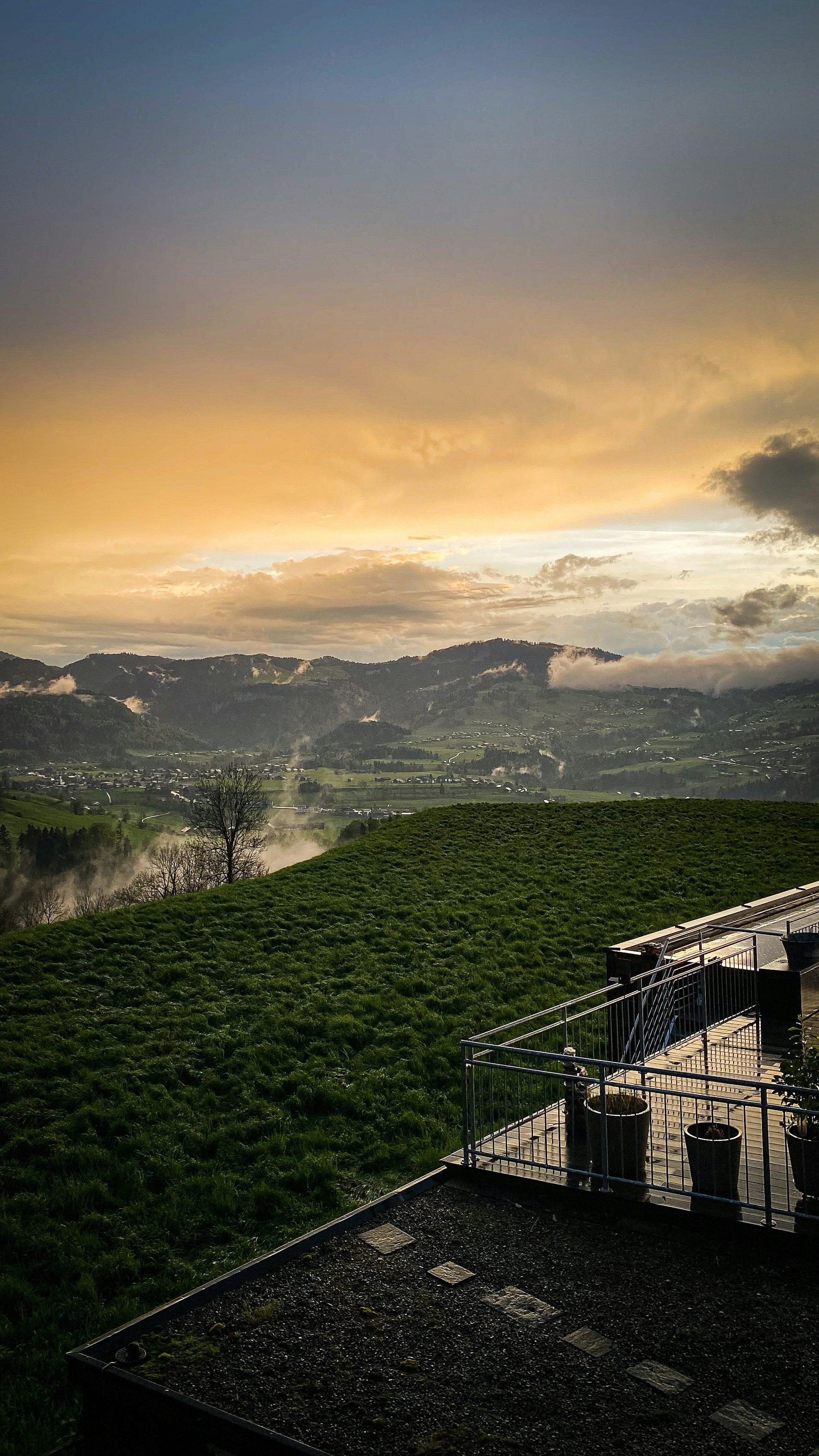 uma vista de um campo gramado e montanhas ao pôr do sol