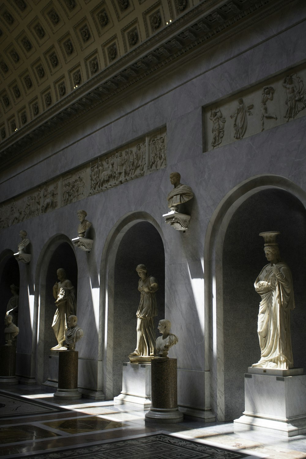 a group of statues in a room with arches