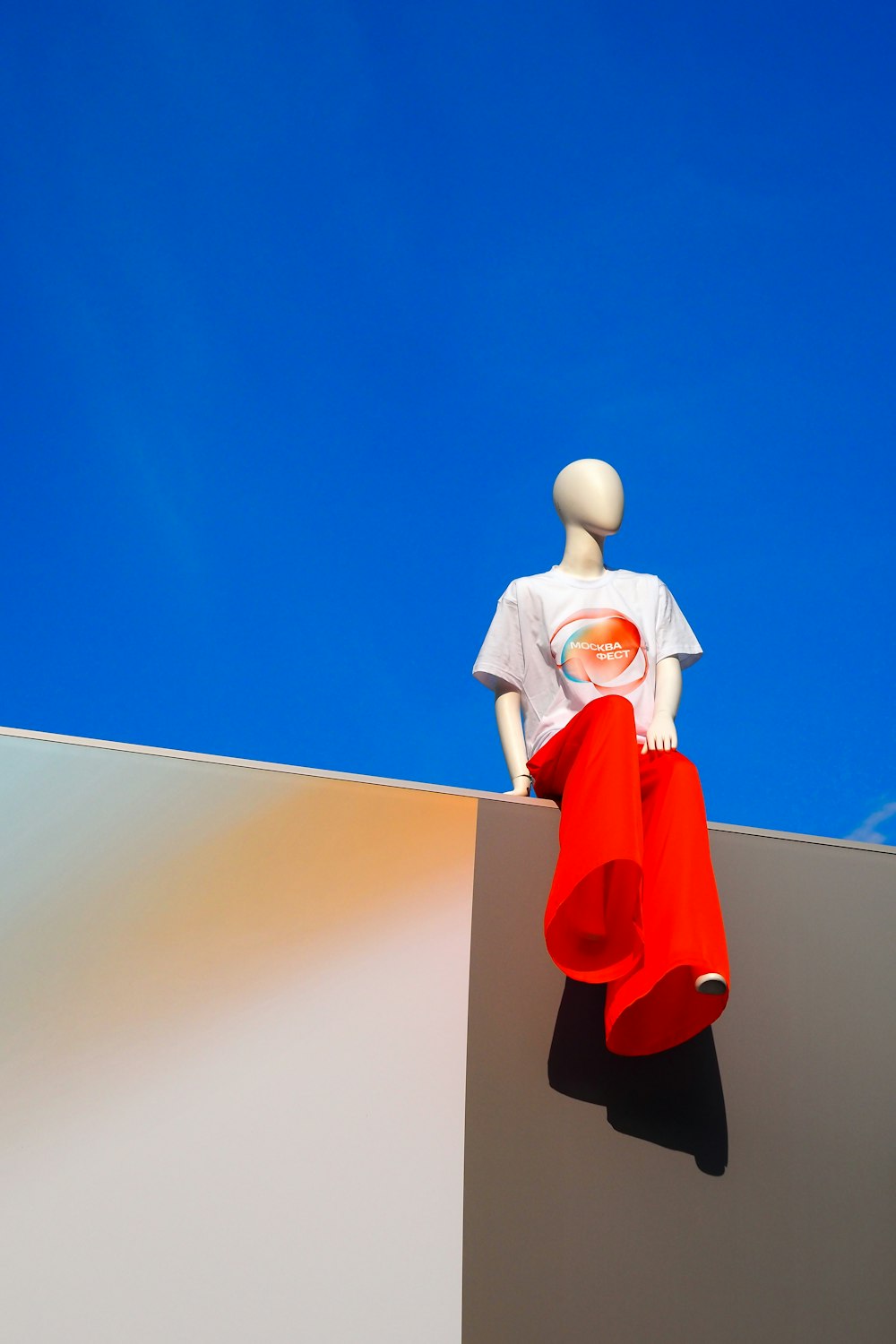 a mannequin sitting on top of a white wall