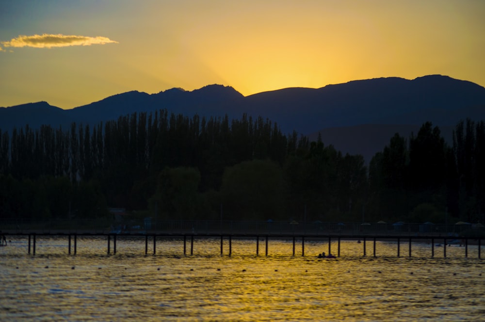 Die Sonne geht über einem See mit Bergen im Hintergrund unter