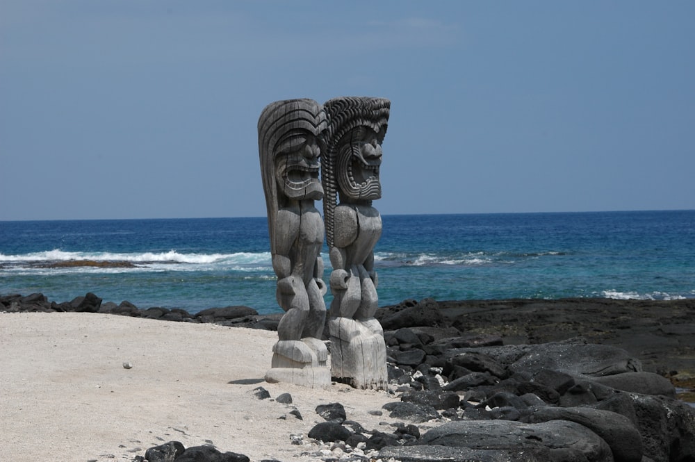 um par de estátuas sentadas no topo de uma praia de areia