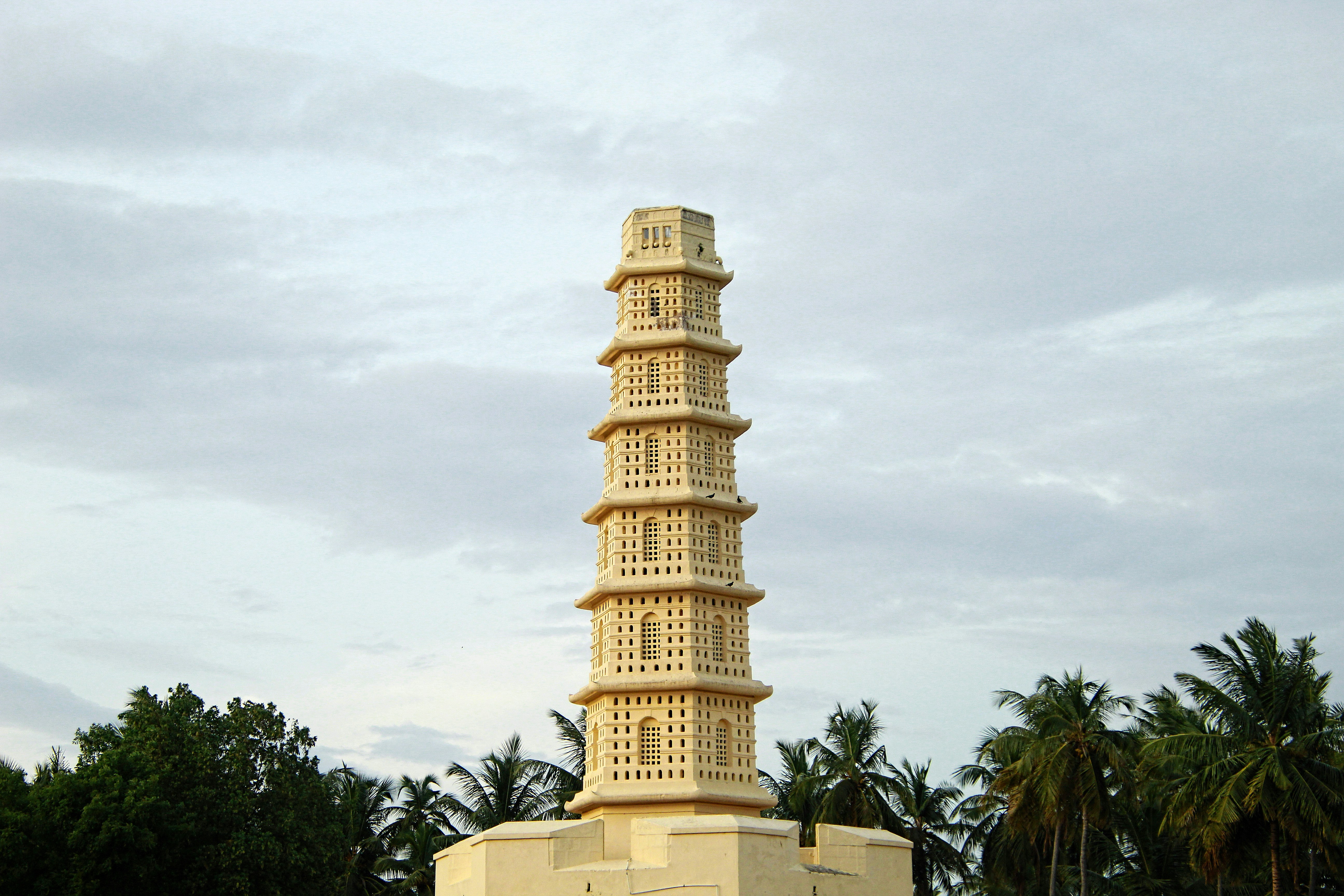 a tall white tower sitting next to a lush green forest