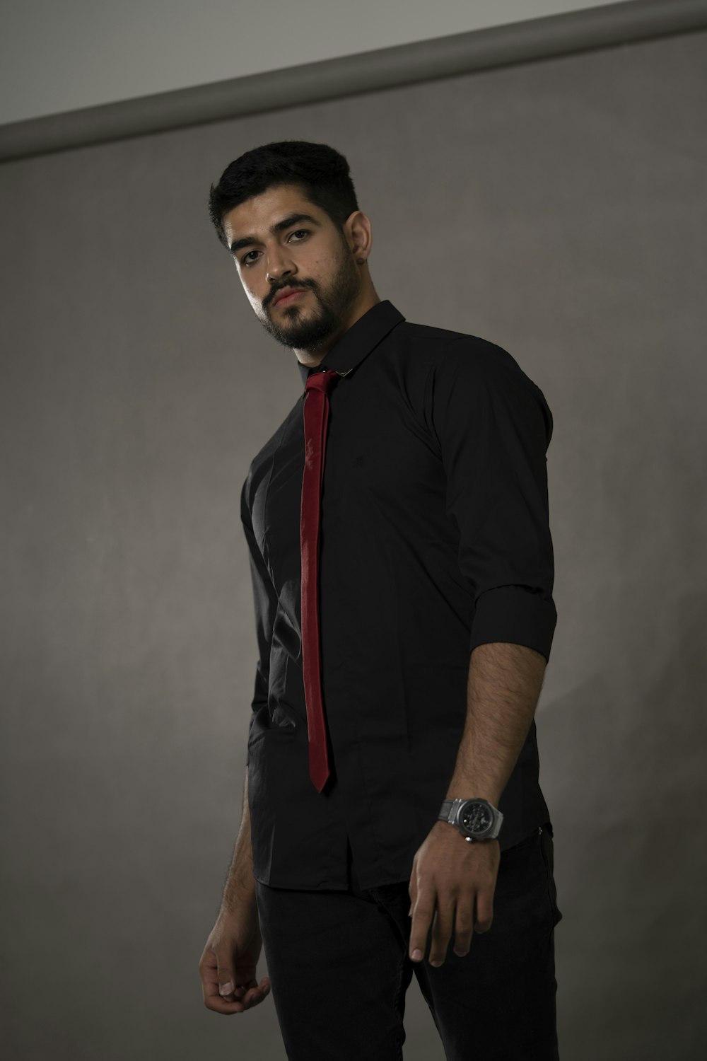 a man in a black shirt and red tie