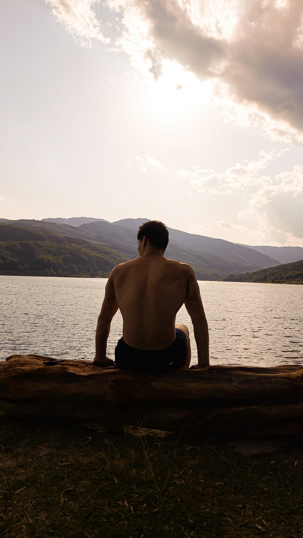 a man sitting on a log looking at the water