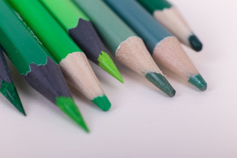 a group of green and black pencils on a white surface