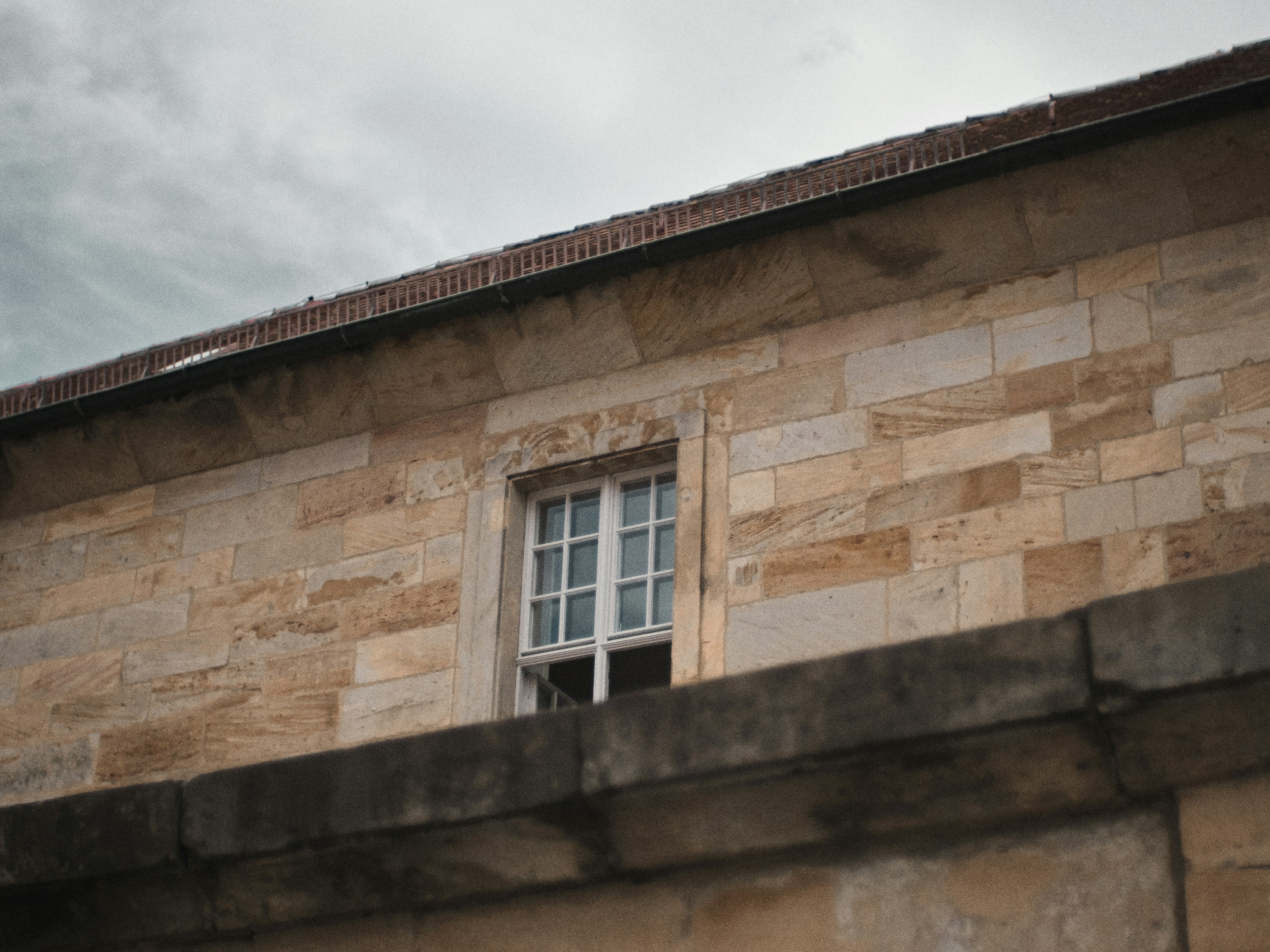 a brick building with a window and a sky background