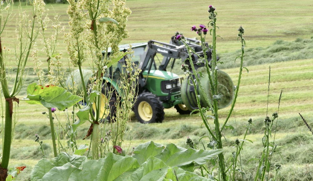 a green tractor driving through a lush green field