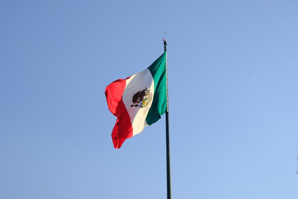 a mexican flag flying in the wind on a pole