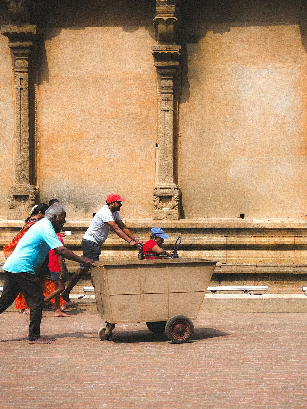 a group of people pushing a cart with a baby in it