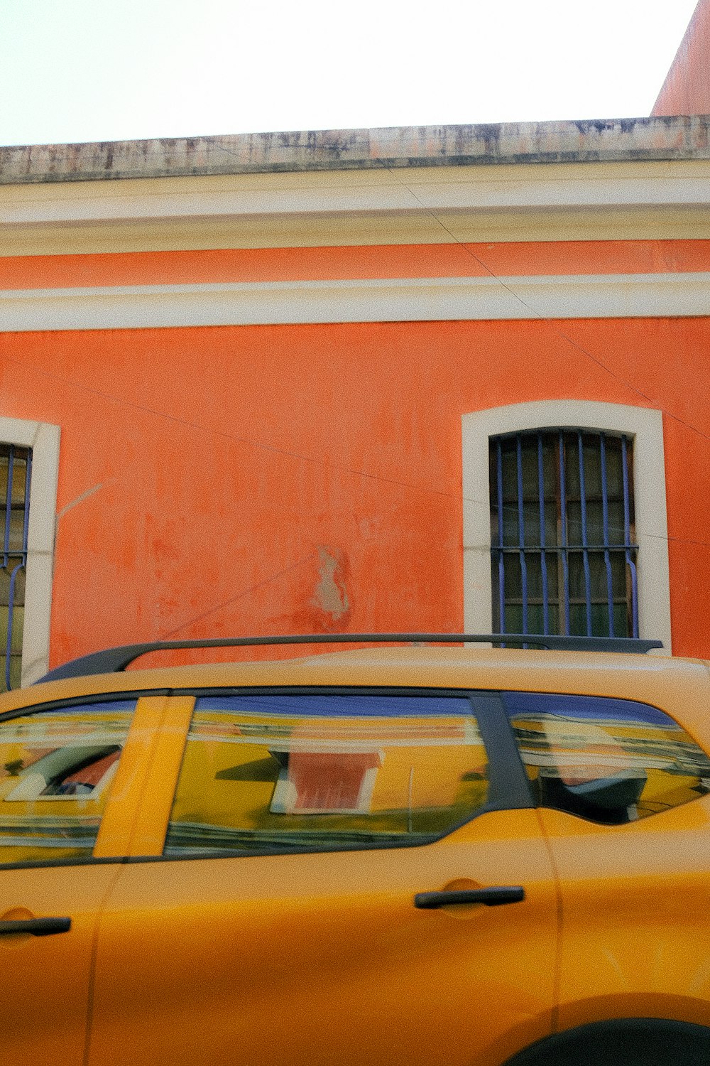 ein gelbes Auto, das vor einem roten Gebäude geparkt ist