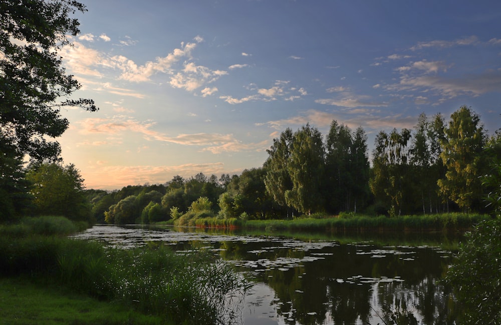 the sun is setting over a small lake