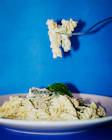 A plate of creamy pasta topped with cherry tomatoes and basil, served on a green and white tablecloth.