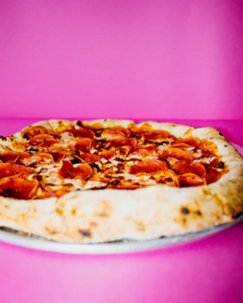 A vibrant pepperoni pizza with golden crust served on a traditional ceramic plate.