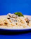 Close-up of a black box filled with creamy truffle pasta, garnished with fresh herbs and a golden fork.