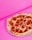 A pepperoni pizza is placed against a vibrant pink background, showcasing a mix of crispy, charred crust and melted cheese topped with slices of pepperoni.