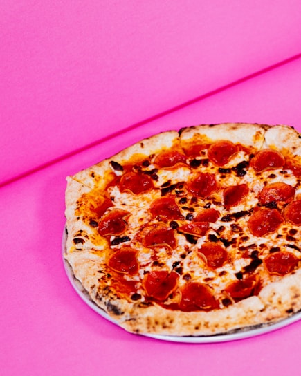 A vibrant red background with a close-up of a cheesy pepperoni pizza slice.