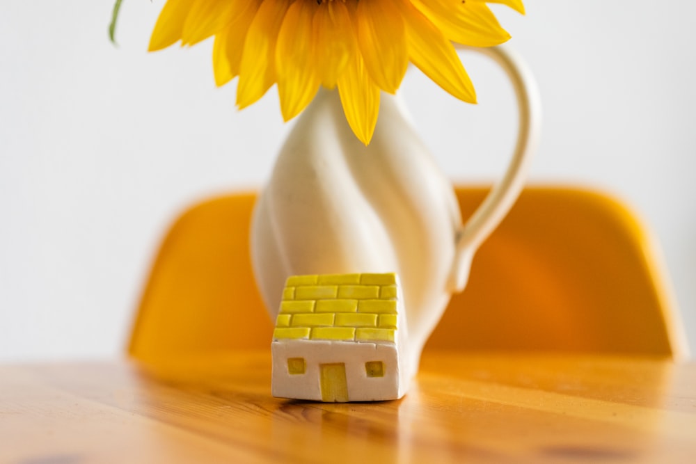 a sunflower in a vase with a small house on it