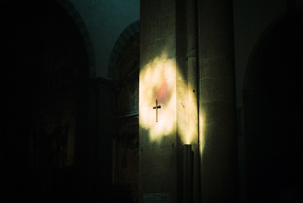 a cross on a wall in a dark room