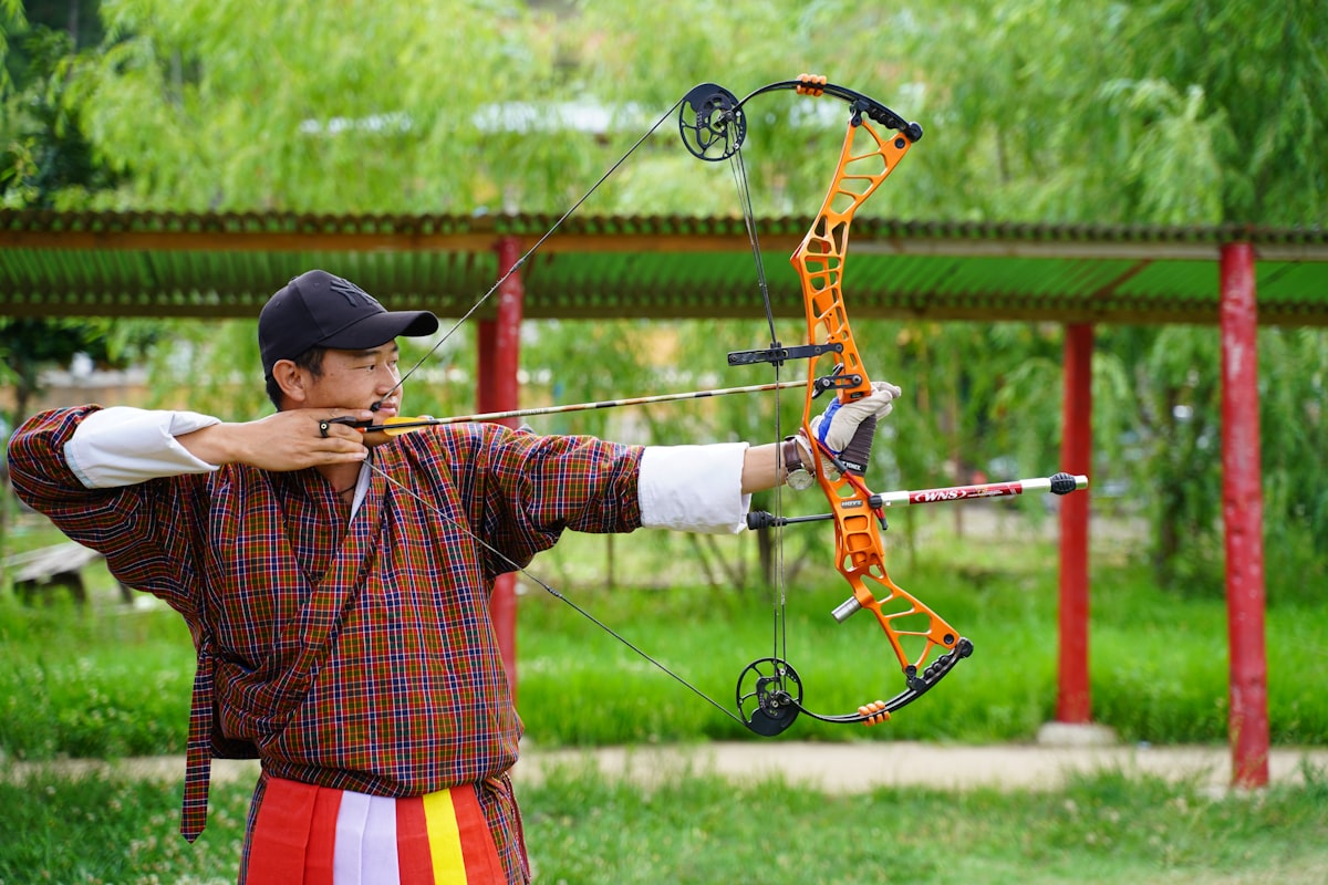 Bowhunter drawing compound bow and aiming at target